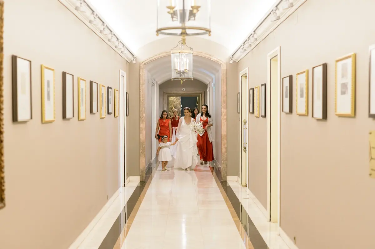 Bride walking down the aisle on her wedding day, surrounded by photographs of celebrities who have stayed at Palácio Estoril Hotel.