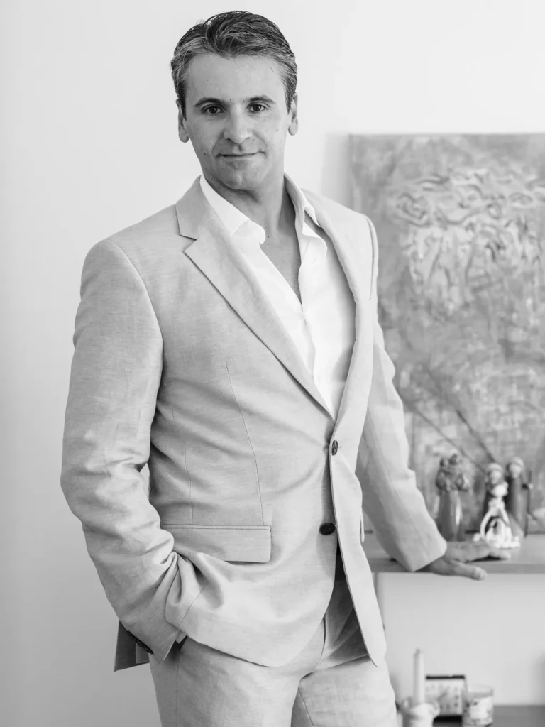 Retrato documental do noivo Alexandre a preparar-se em casa, vestindo um elegante fato de linho bege, antes do seu casamento na praia.