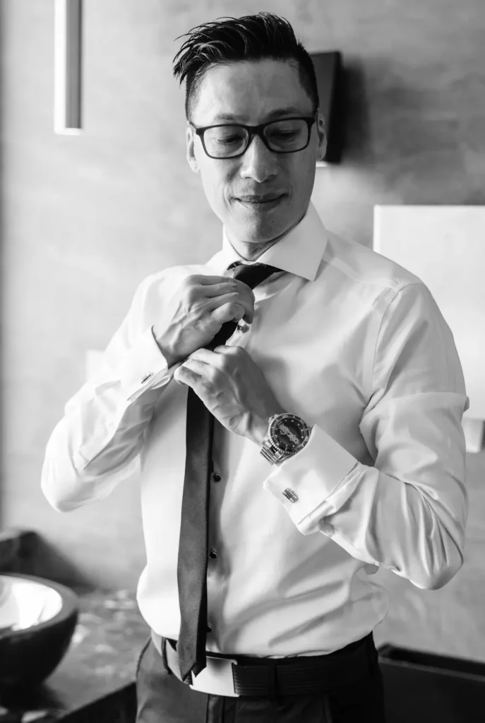 Noivo Bryan a preparar-se num balneário de mármore com luz natural, fotografia de casamento fine art no Estoril.