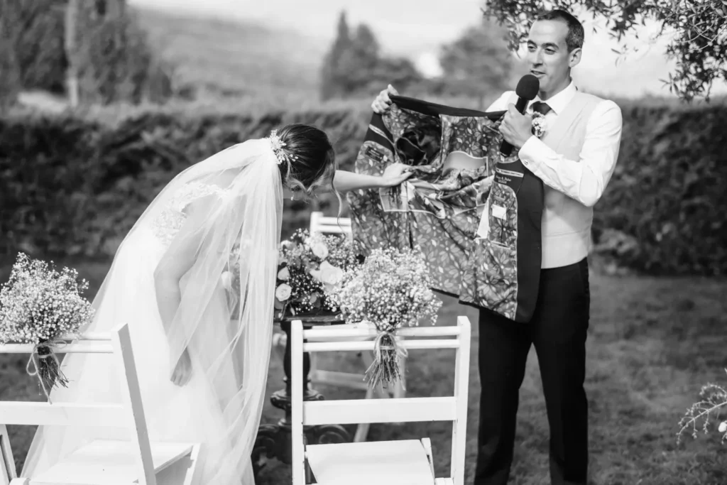 Noivo Pedro mostra forro de casaco personalizado com fotografias surpresa durante a cerimónia de casamento.