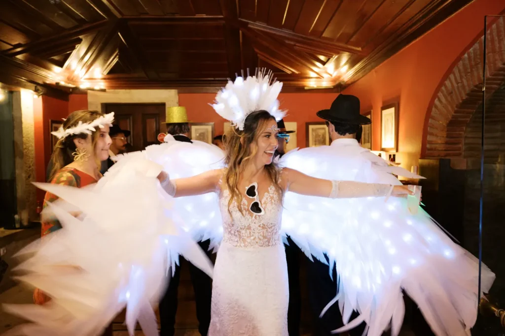 Noiva Mapa com asas de anjo a dançar na pista durante a Hora Loca de casamento de inspiração colombiana.