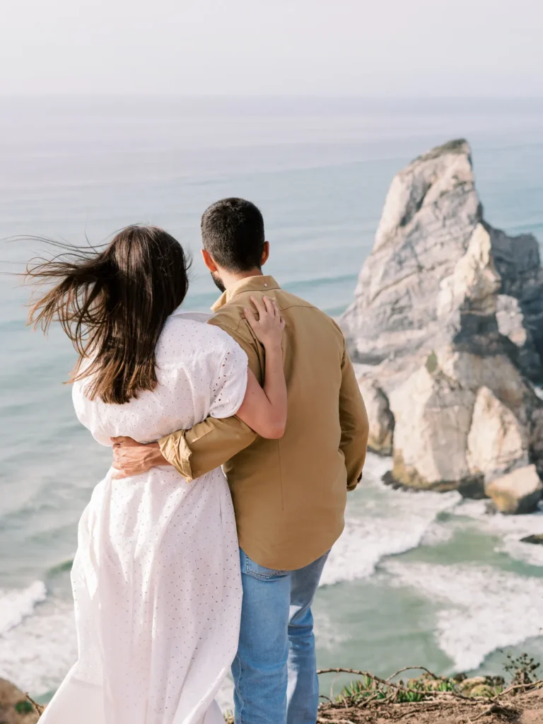 Fotografia documental de noivos com falésias dramáticas e rochedos na Praia da Ursa em Portugal.