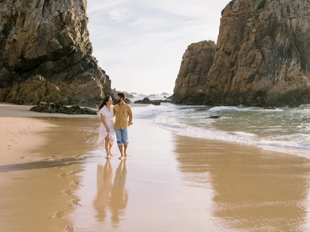 Casal aventureiro a caminhar na Praia da Ursa em Sintra, sessão de noivado fine art.