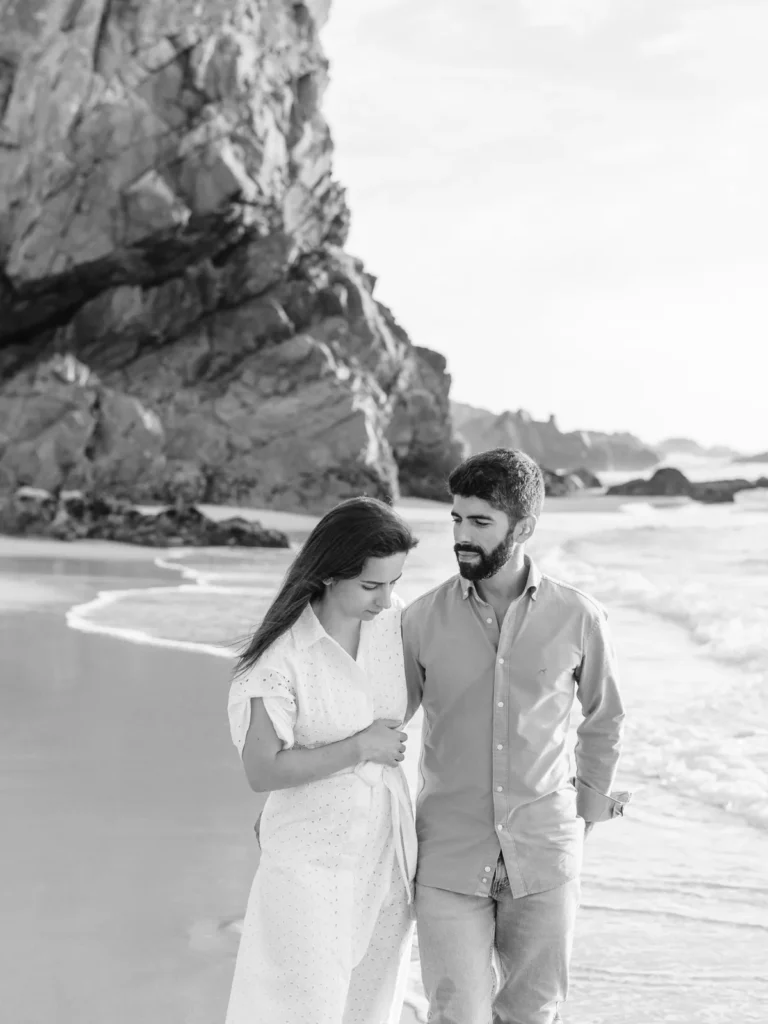 Casal aventureiro a caminhar na Praia da Ursa em Sintra, sessão de noivado fine art.