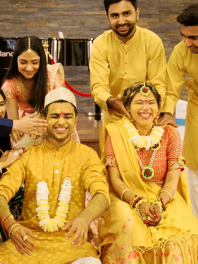 Momentos de pura alegria e gargalhadas durante o ritual de Pithi, com a família a aplicar a pasta amarela de açafrão aos noivos num casamento indiano.